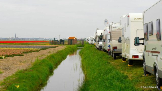 Bobiler parker på rekke og rad ved en smal vei.