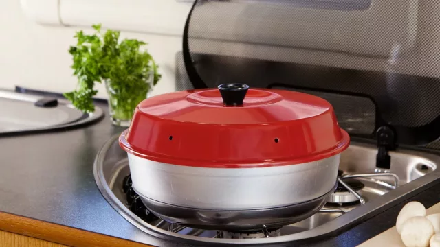 Omnia-ovnen har en rund form med en rød overdel og en sølvfarget base. Det er en slags mini-ovn som kan brukes på en komfyrtopp, enten det er gass eller elektrisk.